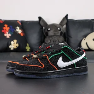 Side angle of Bronx Girls Skate x Nike Dunk Low SB ‘Mel & Kava’ showcasing black textured upper with red and green piping and white Swoosh