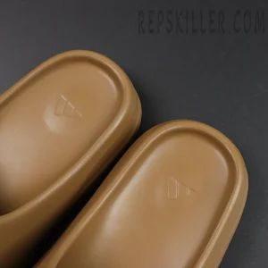 Side angle of the adidas Yeezy Slides ‘Soot’ placed in front of original box packaging.