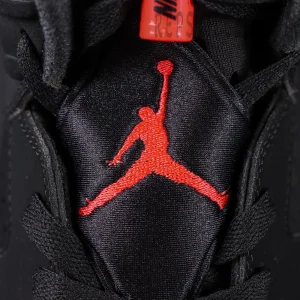 Jordan 6 “Reverse Infrared” Black / Light Crimson tongue close-up showing embroidered red Jumpman logo on black satin.