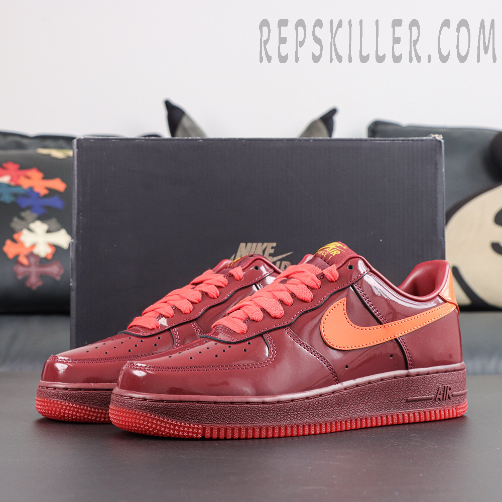 Nike Air Force 1 Low ‘Patent Leather Dark Team Red’ pair display featuring dark red patent leather, orange accents and an all-red outsole