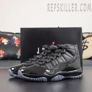 Comme des Garçons x Air Jordan 11 Retro ‘Black’ pair displayed with a black Jordan shoebox, featuring black leather uppers and glossy patent leather mudguards